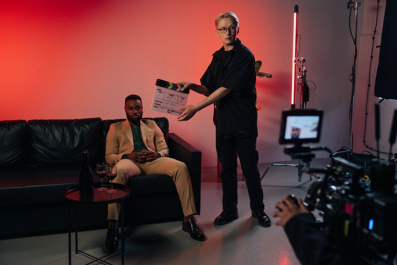 Professional film set with actor in suit, director using clapperboard.